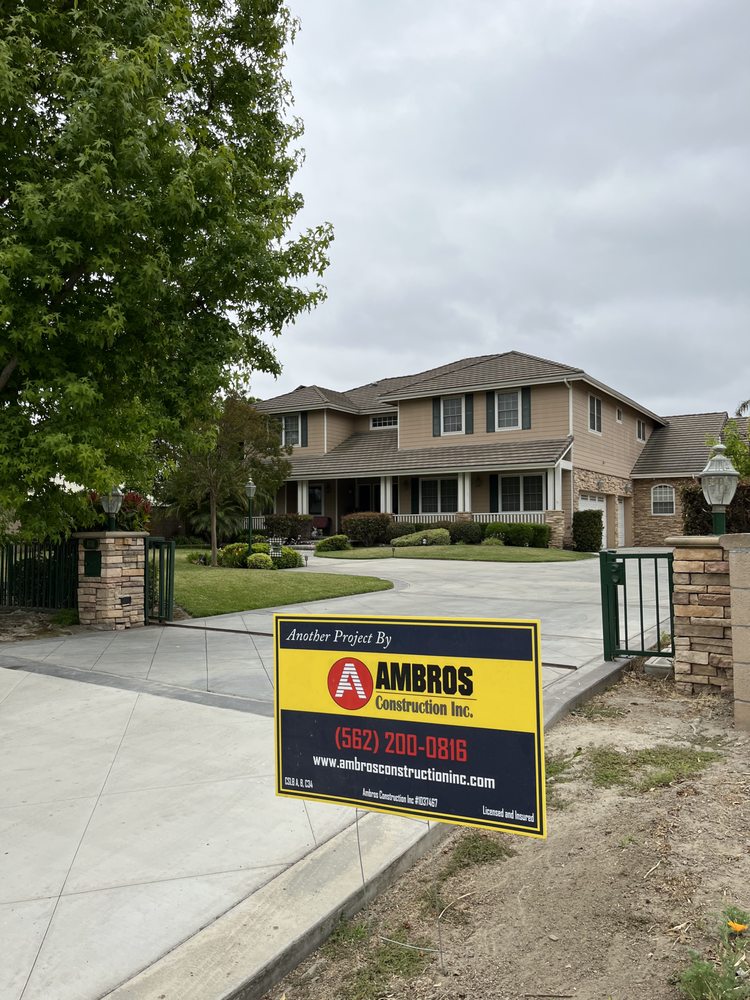 Completed residential concrete driveway with an Ambros Construction project sign